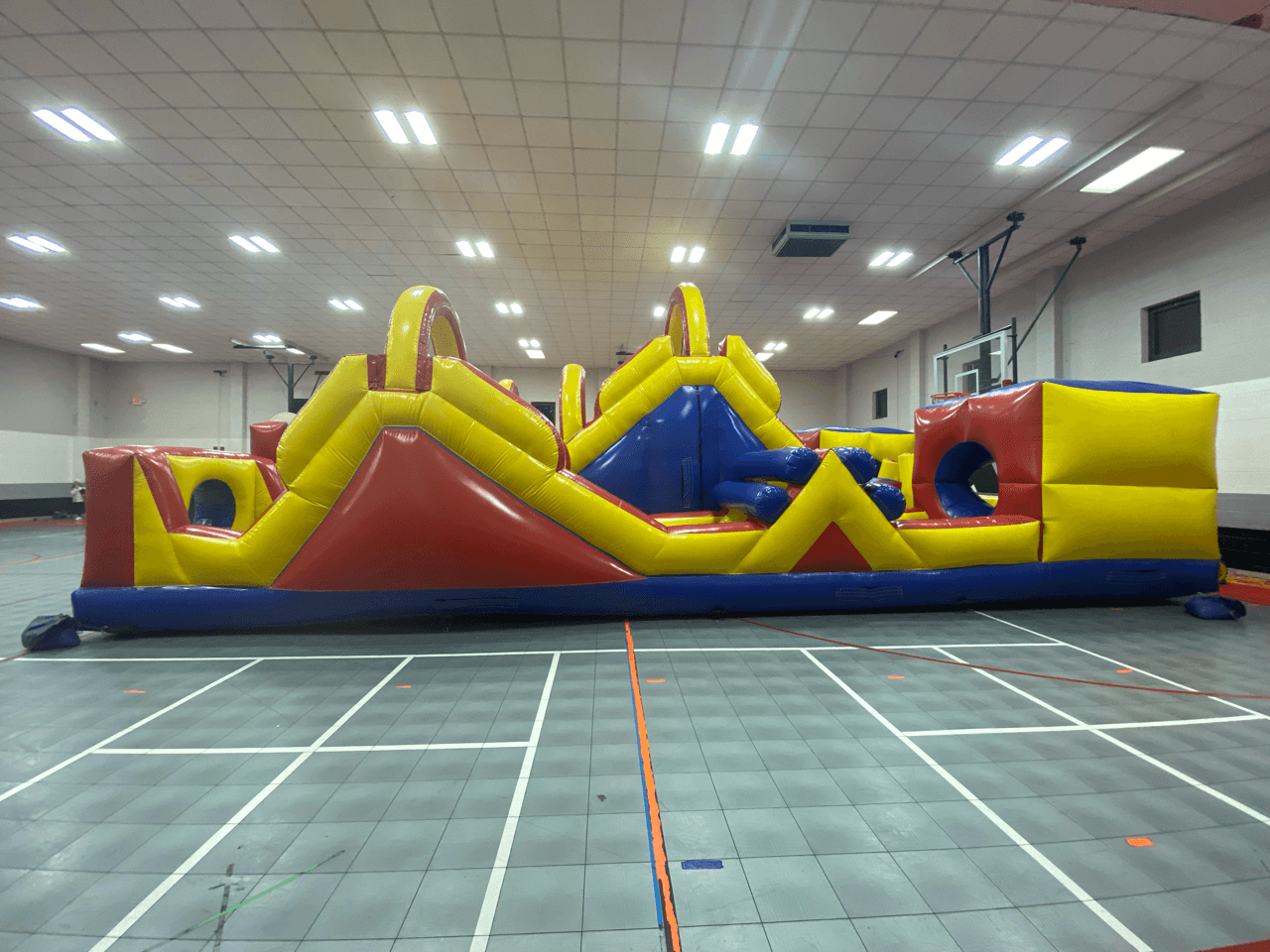 A large inflatable obstacle course set up inside a gym.