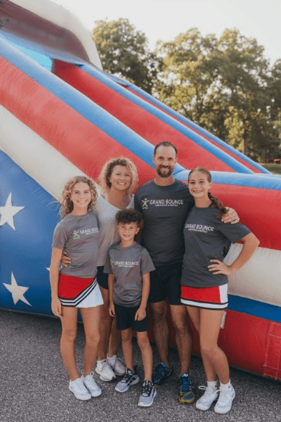 A family portrait in front of a Grand Bounce inflatable.